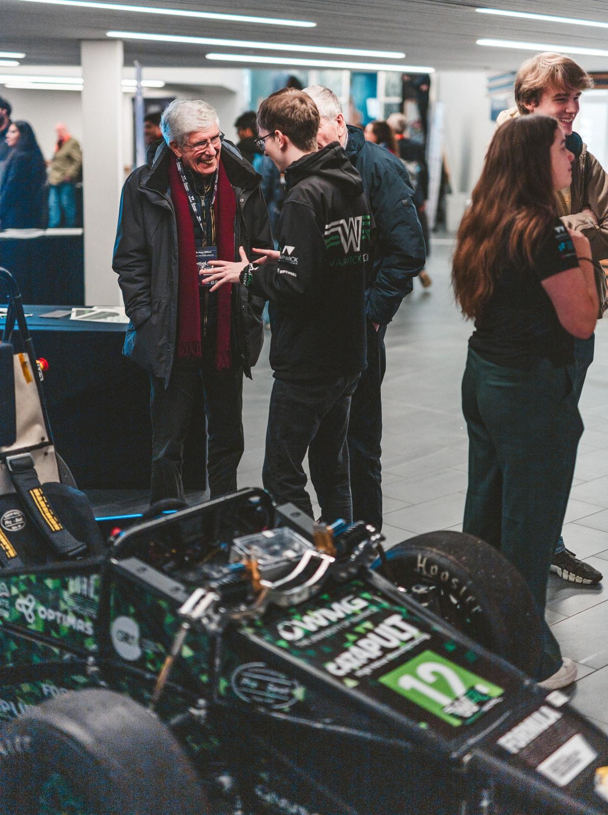 Two men talking standing next to a racing car