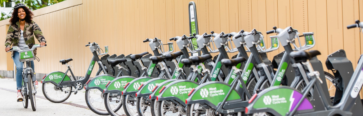 Women riding a west midland cycle and bikes parked in docking stations