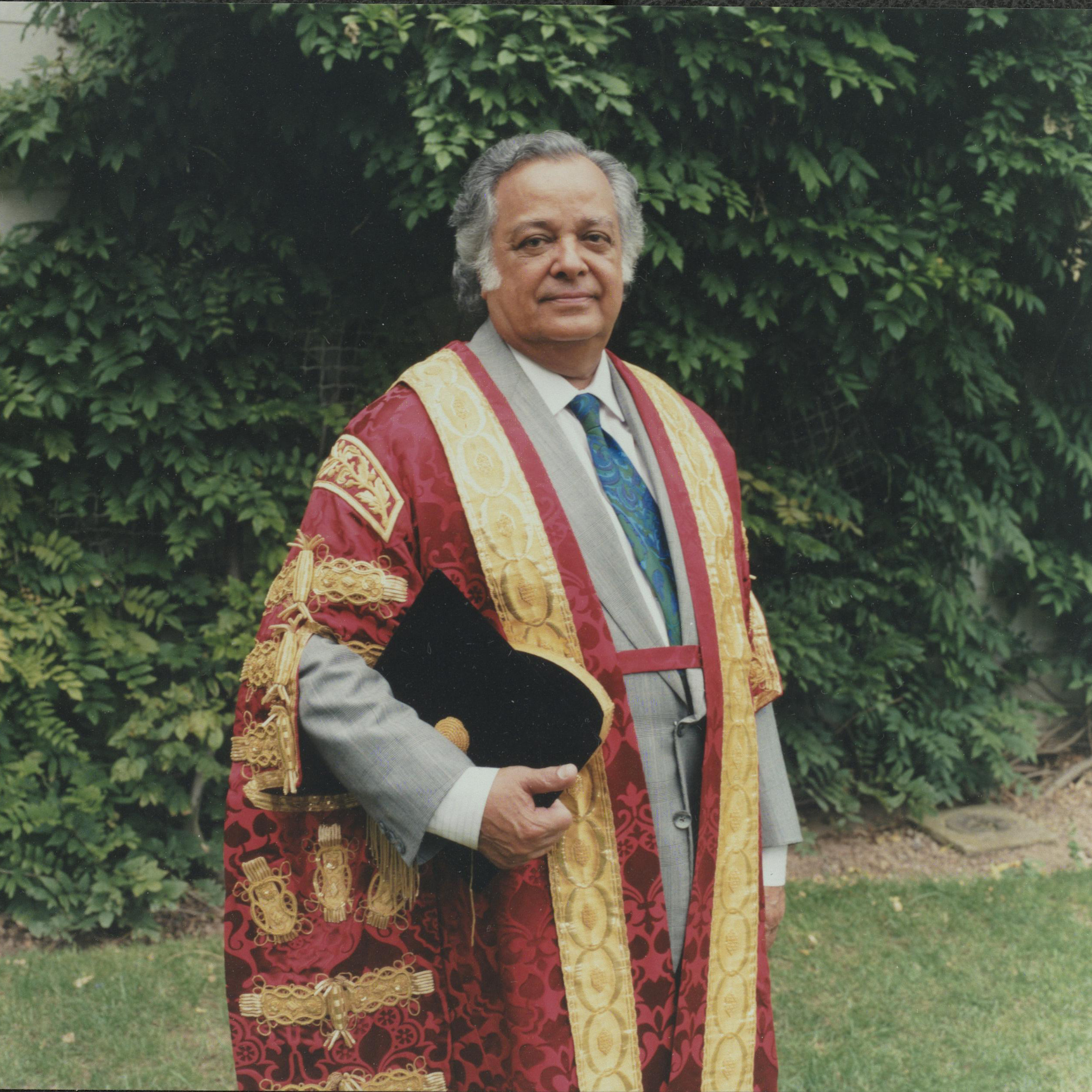 Sir Shridath Ramphal in a gown in front of a hedge