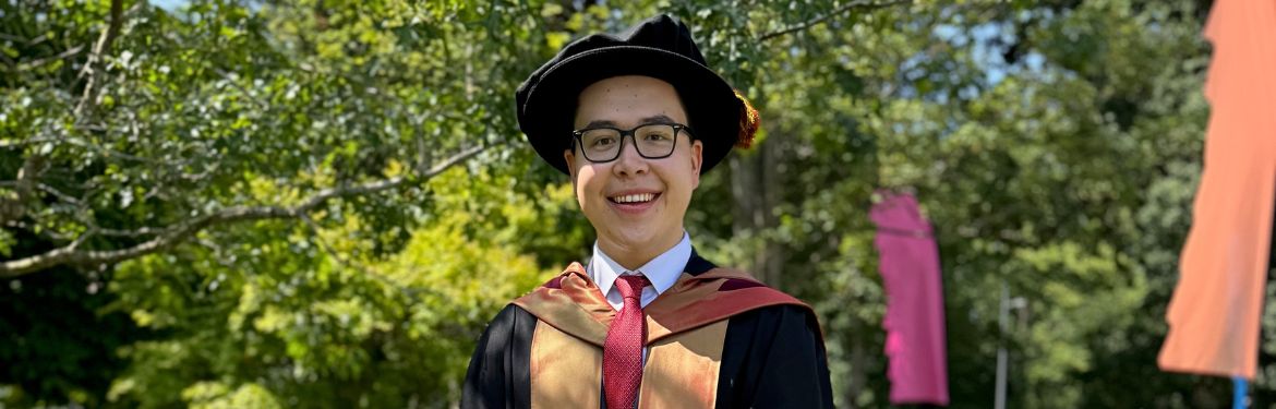 Joe in his graduation robes standing outside