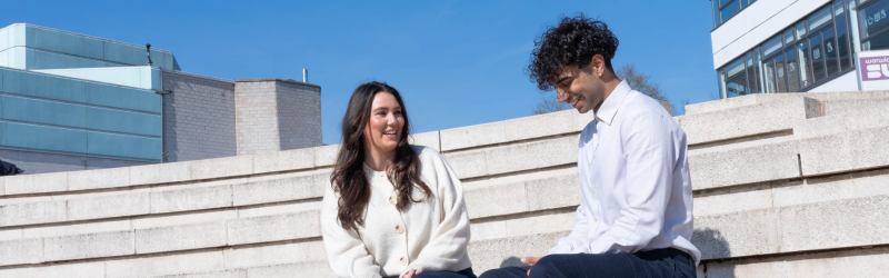 two students sat on steps chatting