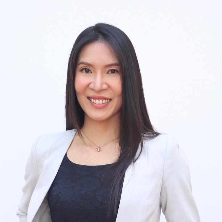 Arada smiles at camera in an off-white blazer and blue top