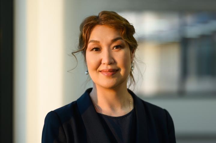 Gulnara smiles at camera. She wears her up up and has silver earrings