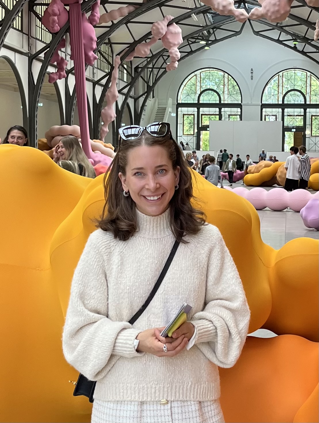 Maximiliane stands in front of a yellow sculpture smiling
