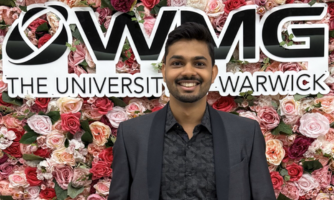 Rahul in front of WMG branding surrounded by pink flowers