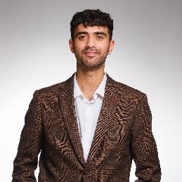 Saahim wears a brown blazer over a white shirt