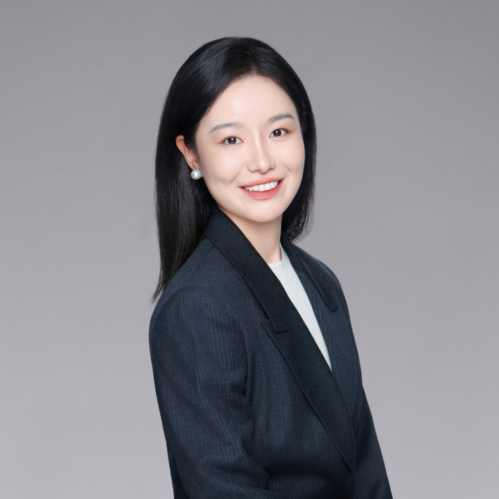 Samantha stands sideways and looks to camera wearing a dark blue blazer