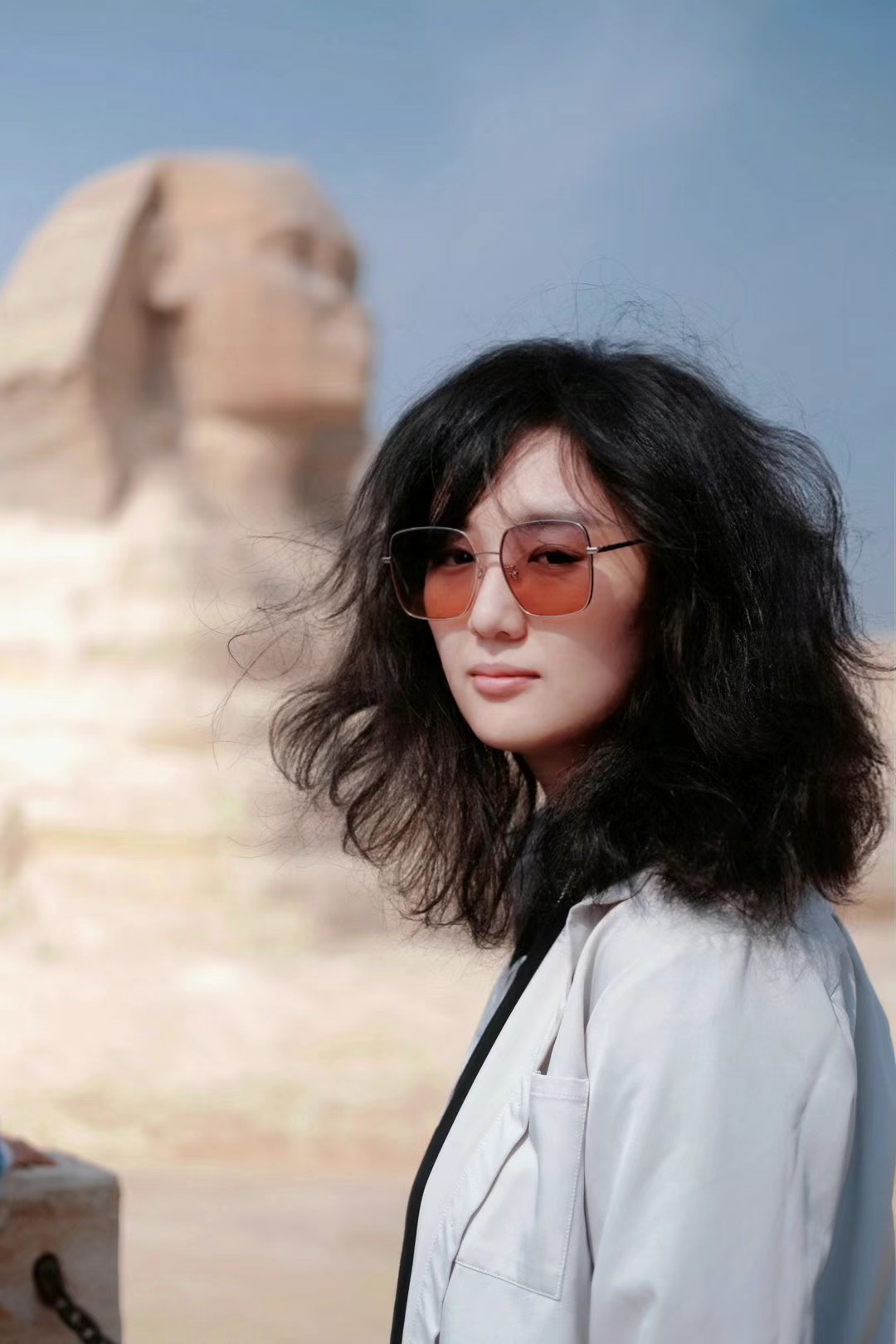 Sihan wears red sunglasses and poses in front of the Sphynx
