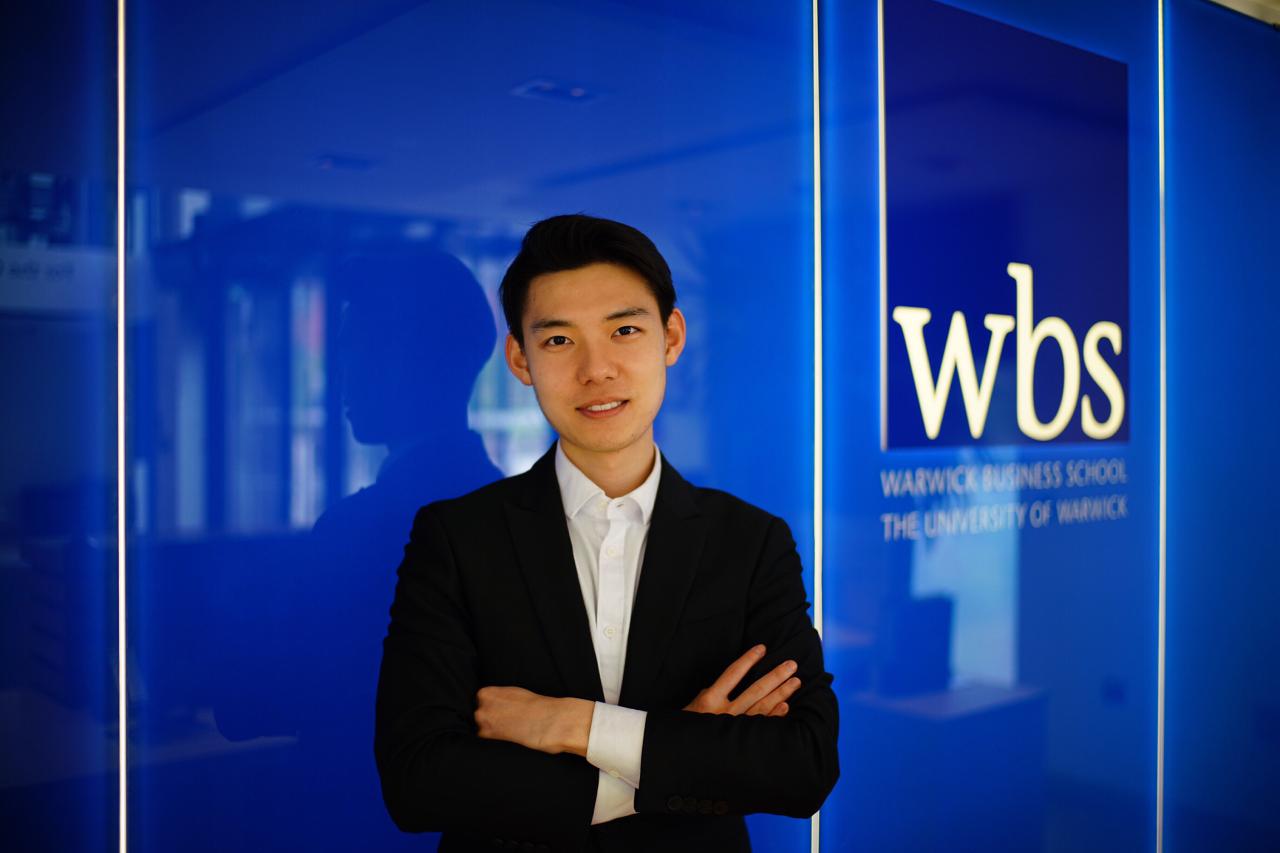 Zeyu stands before a WBS sign