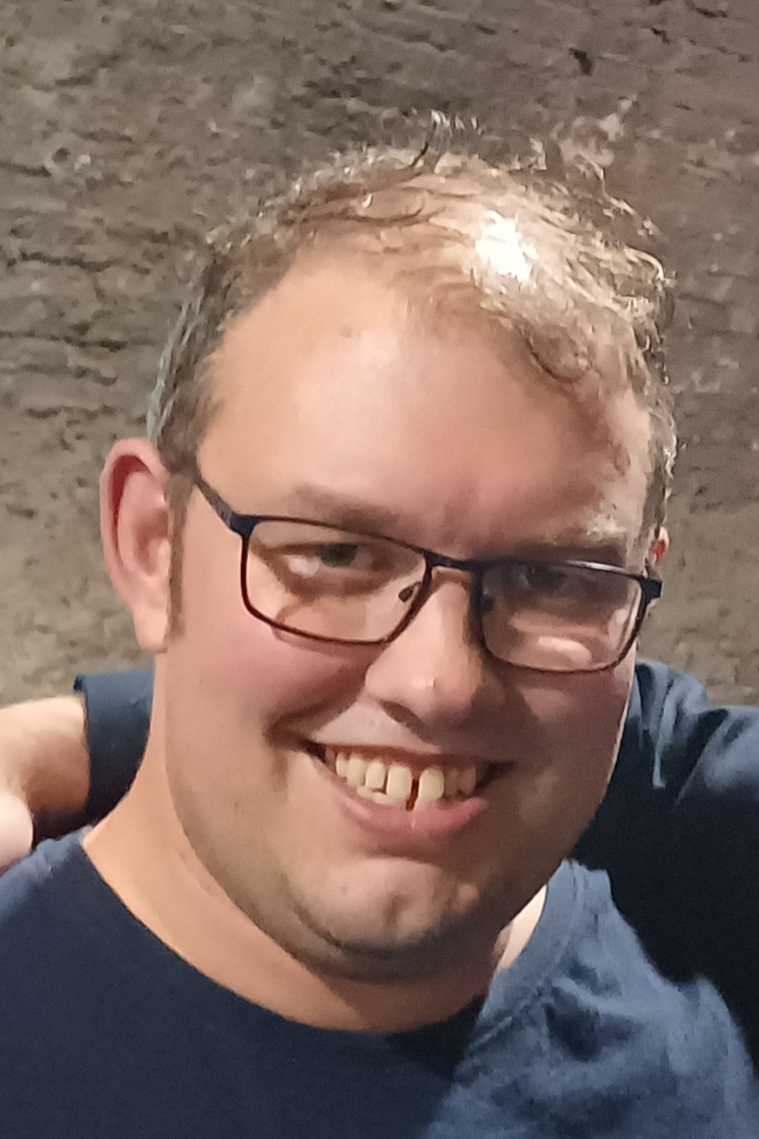 Daniel smiles in a pair of square glasses