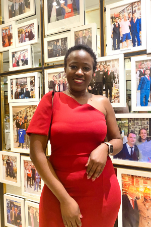 Anittah stands in a red dress before a wall of photographs