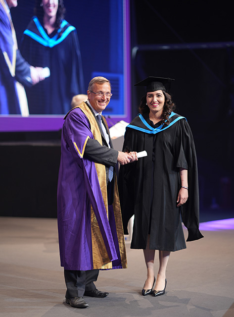 VC Stuart Croft and Amina on stage during graduation ceremony shaking hands on stage looking happy 