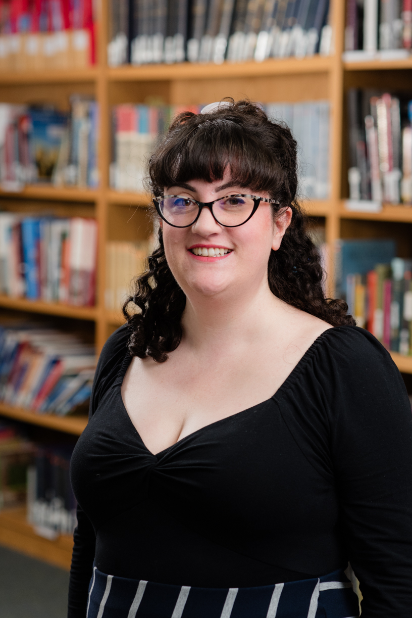 Caroline smiling in front of a wall of books