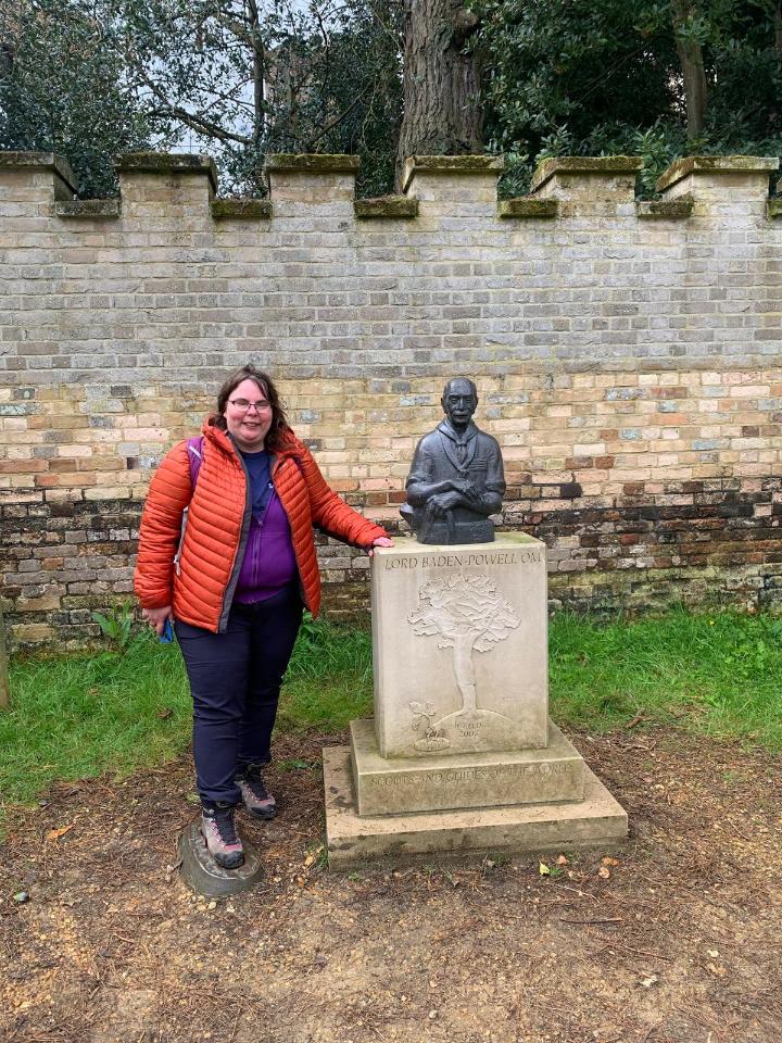 Linda next to a statue in a red coat