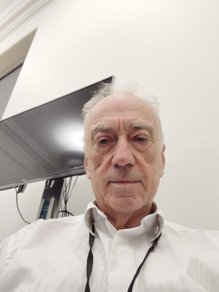 Paul wearing a white shirt looking down at camera