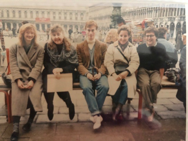 Amanda and friends sit on a bench in coats