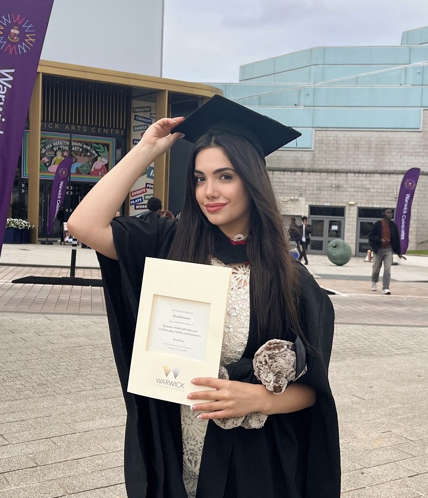 Ella holding her degree certificate at her graduation