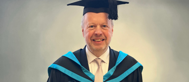 Andy in his graduation robes with a blue hood