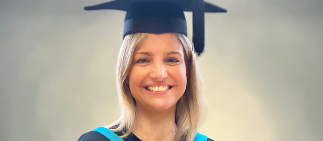 Eszter in graduation robes with a blue hood