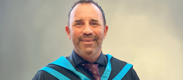 Jim in his graduation robes with a blue hood