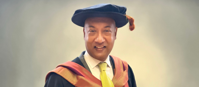 Orlando in his PhD graduation robes with a orange hood