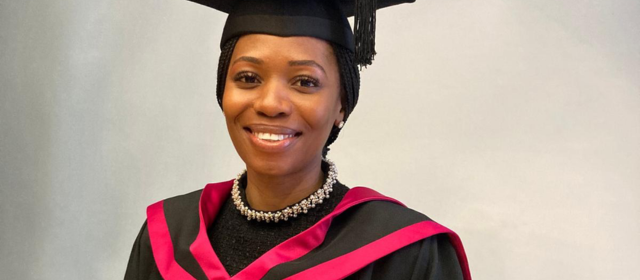 Rumbie in her graduation robes with a red hood