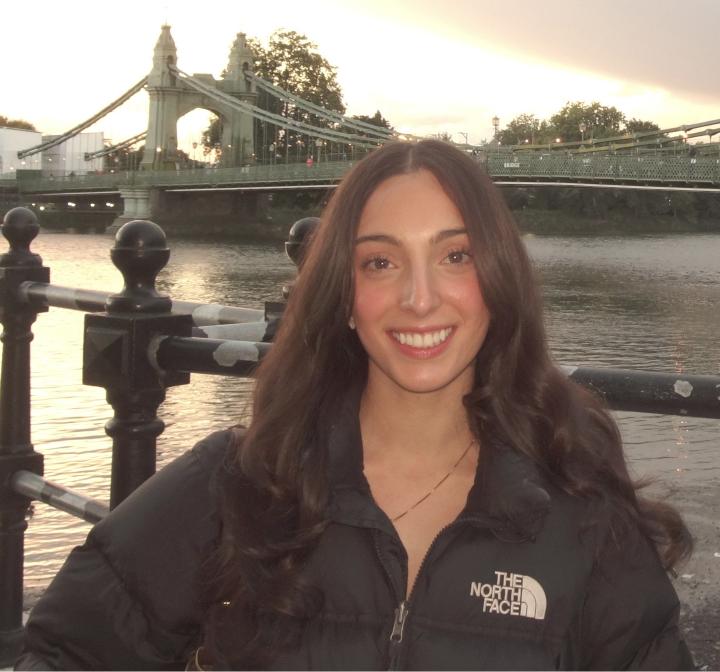 Chiara stands before a bridge at sunset