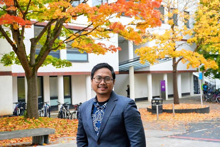 Iqbal on campus with autumn trees in the background