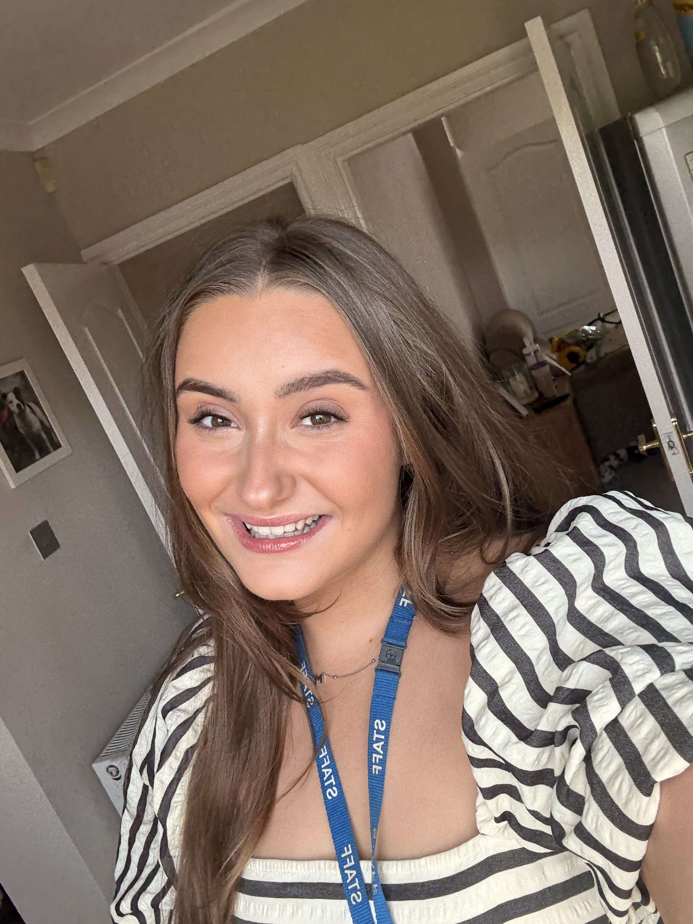 Molly smiles at camera wearing a green and cream striped dress and a blue lanyard around her neck