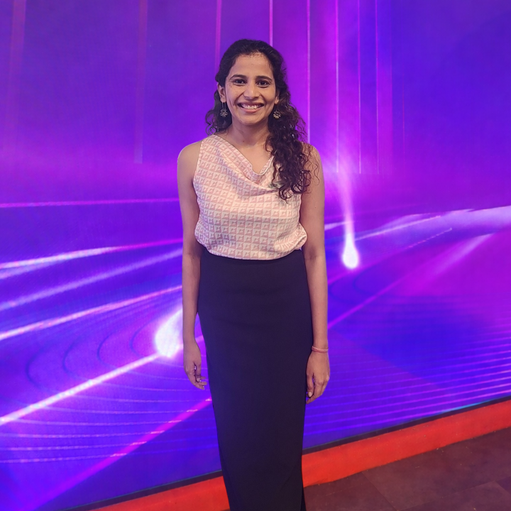 Prerita stands in front of a screen that's pink and purple 