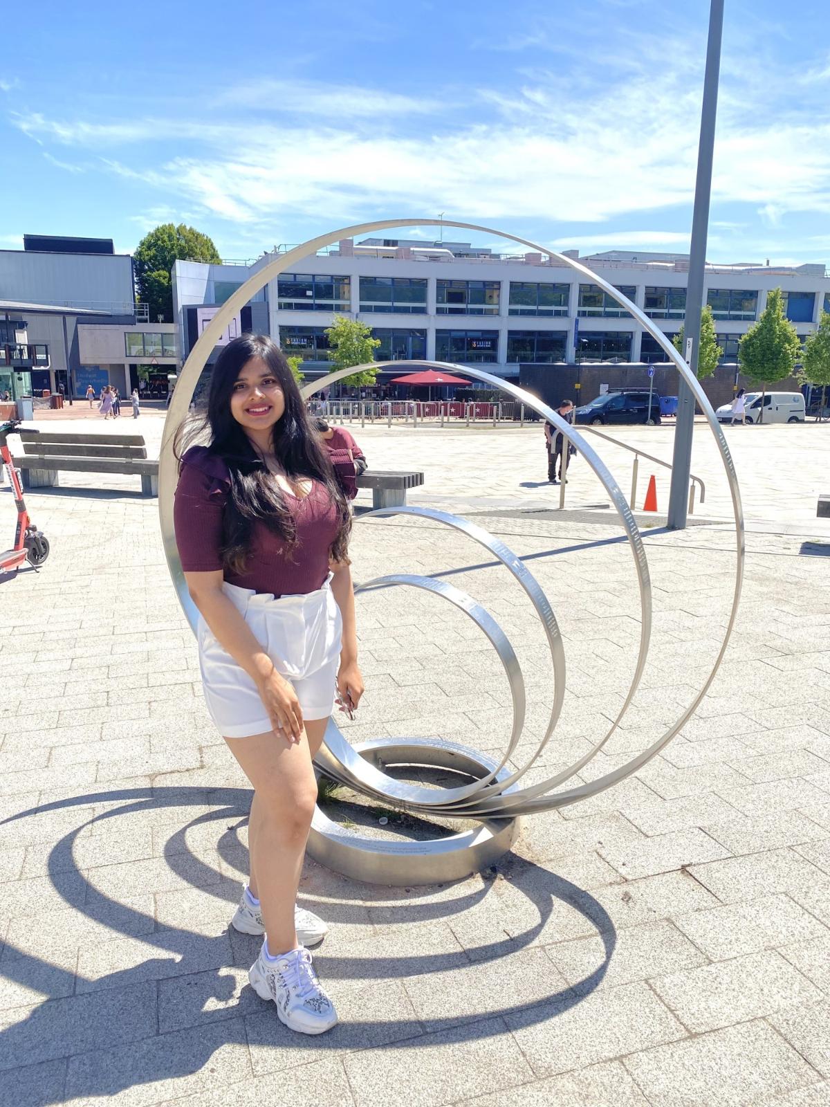 Devika Ghosal standing next to a sculpture on Warwick campus