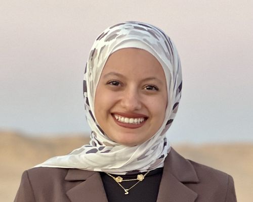 Samar wears a white and grey spotted hajib and smiles at camera