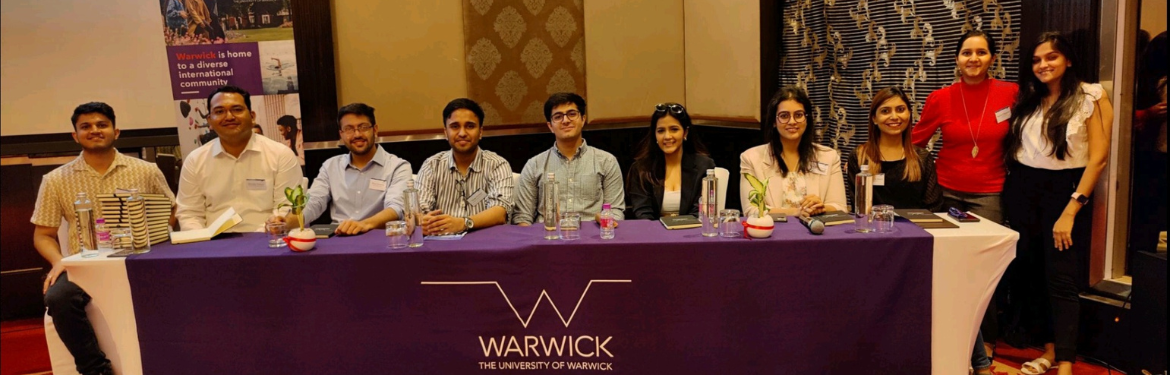 Volunteers sit around a table with a Warwick tablecloth