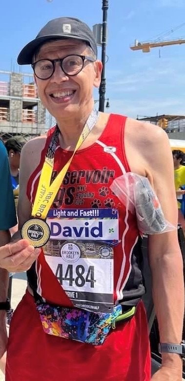 David smiles at camera and holds medal after finishing the marathon