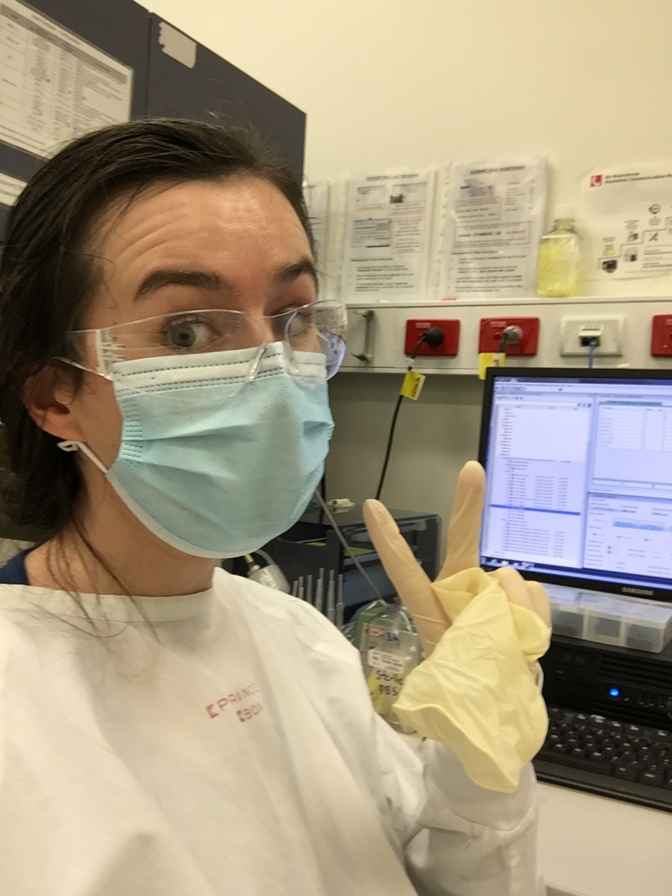 Emily in a lab wearing protective goggles and a mask