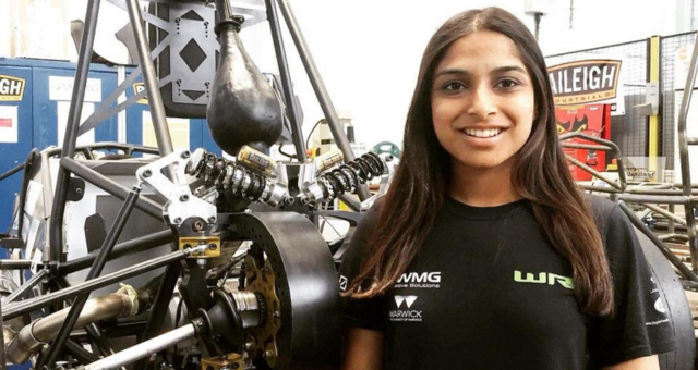 Disha standing in front of mechanical components