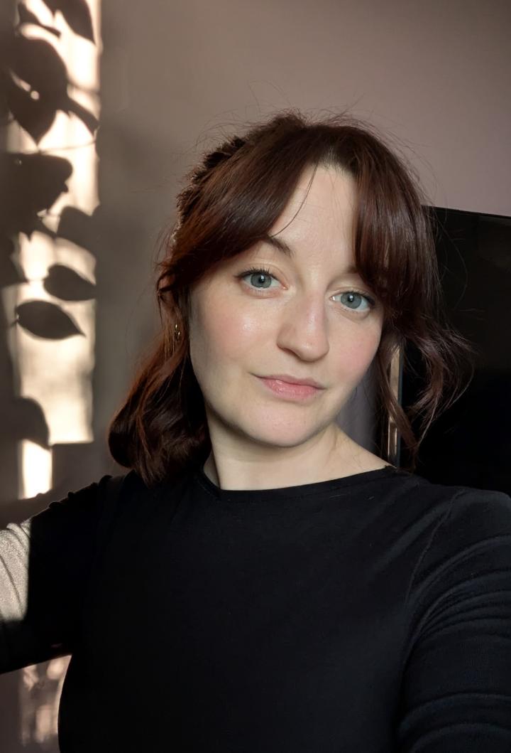 An image of Beth Sharrock, a woman with reddish brown hair and green eyes 