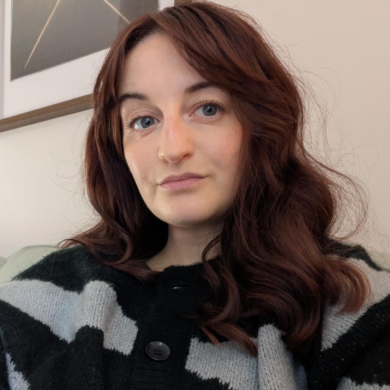 An image of Beth Sharrock, a woman with reddish brown hair and green eyes 