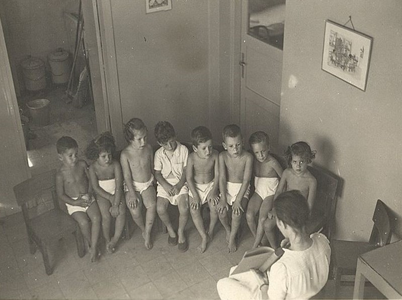 black and white photo of children with teacher in Kibbutz Givat