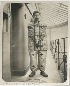 black and white photo of young male prisoner in straightjacket