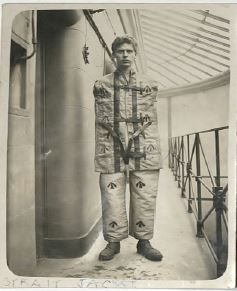 black and white photo of young male prisoner in straightjacket
