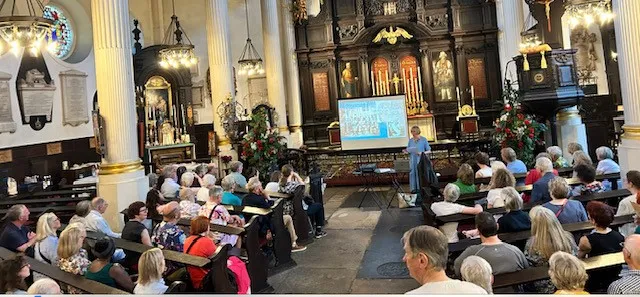 An audience of people watching a talk by Paula Bartley in a Church