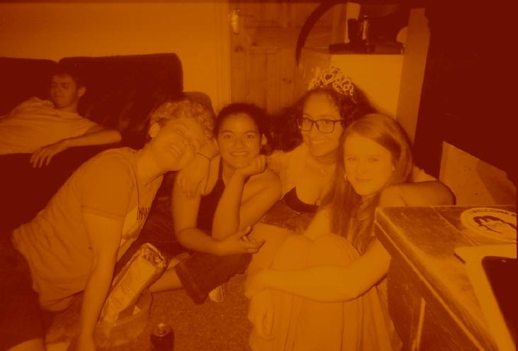 From left to right, David trying to hold his alcohol, Ollie, Christa, a Princess and Bex. An orange tinged photograph of the group crouched on the floor and smiling.