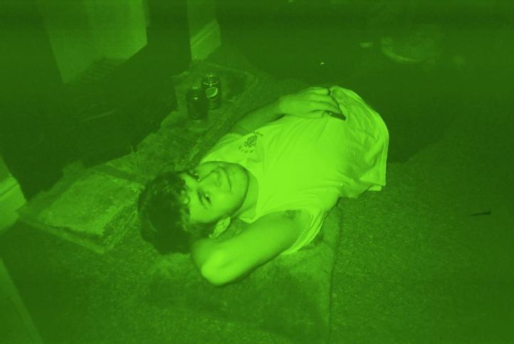 David lying on the floor and looking into the camera. The image is tinted green.