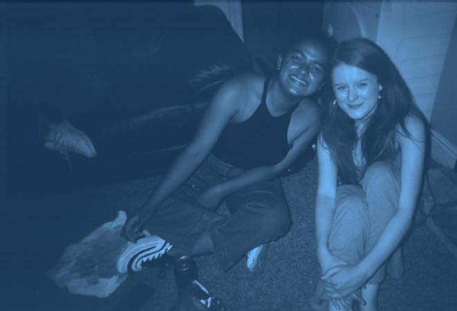 Bex and Christa, both from my different support networks, bonding over astrology. A blue tinted photograph of the two leaned in together and smiling.