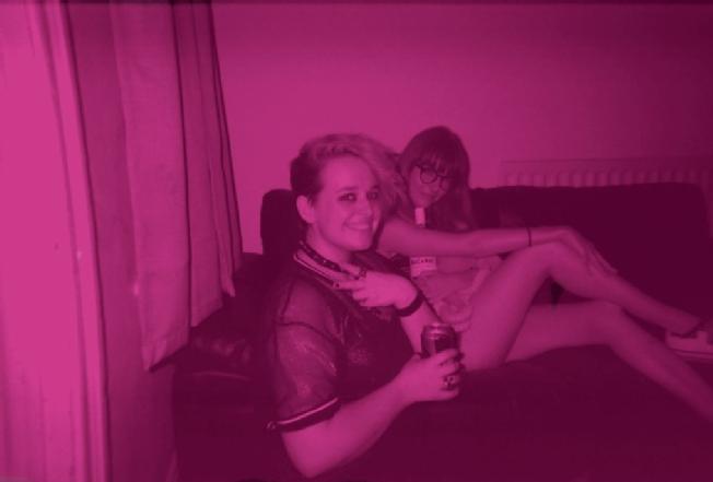 From right to left, Lucy, and her nonbinary housemate Milo. A pink tinged photograph with both posing for the camera.