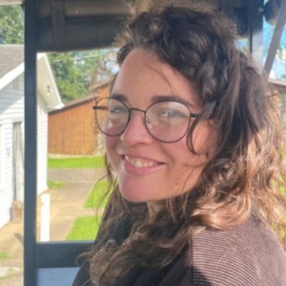 smiling white woman with brown curly hair and black rimmed glasses