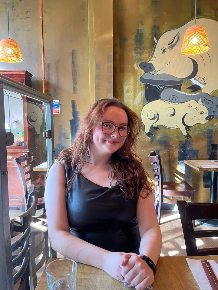 Image of a woman smiling at the camera. She has brown curly hair and glasses.