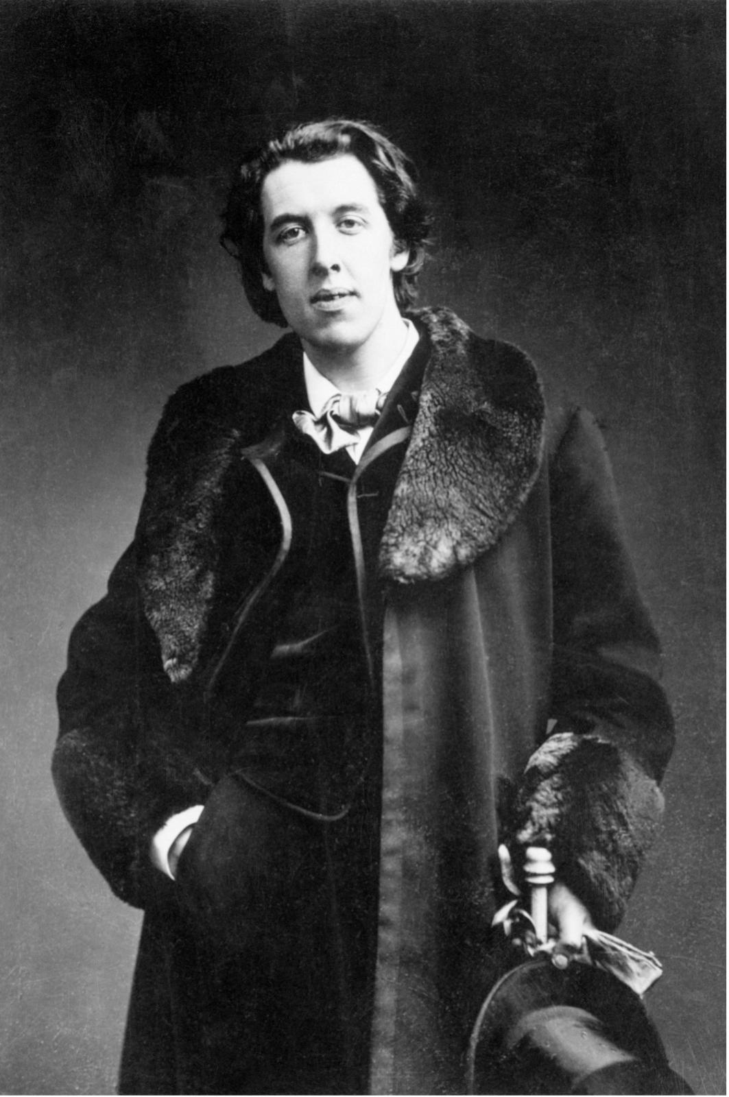 Photograph of Oscar Wilde with his top hat in his left hand and the other in his pocket
