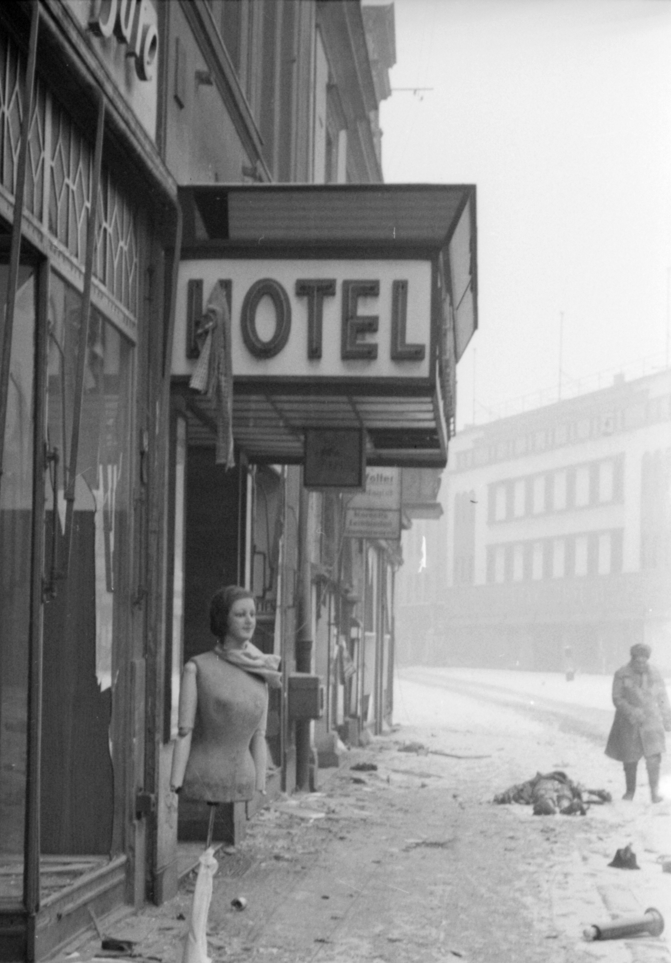 A mannequin stands outside an hotel in a desolate street